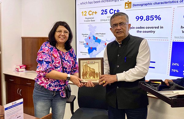 Dr. Pushpa Yadav receiving a framed commemorative plaque from Shri Ashishkumar Chauhan, MD & CEO of the National Stock Exchange of India, during a visit to the NSE.